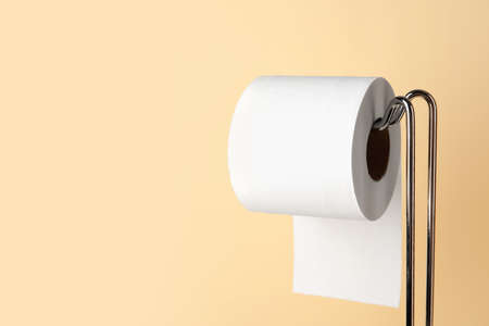 Modern holder with toilet paper roll on beige background, closeupの写真素材
