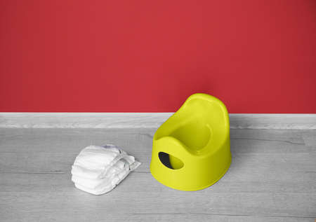Potty and diapers on gray wooden floor near color wallの写真素材