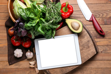 Digital recipe book, greens, vegetables and knife on wooden backgroundの写真素材