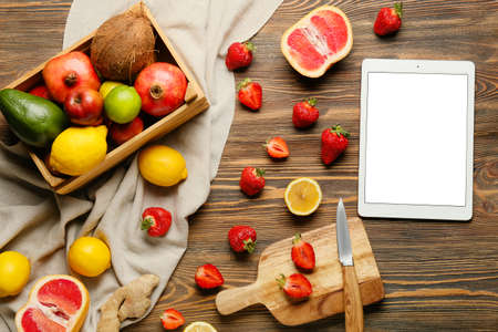 Digital recipe book and different fruits on wooden backgroundの写真素材
