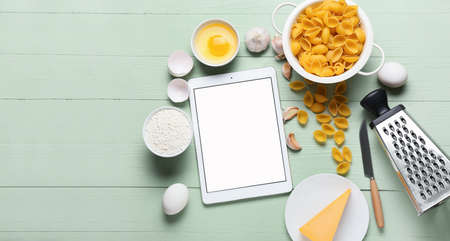 Digital recipe book, kitchen utensils and ingredients on color wooden backgroundの写真素材