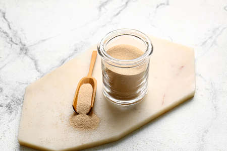 Jar and scoop with active dry yeast on light backgroundの写真素材