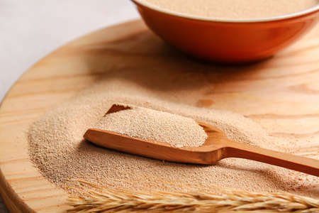 Scoop with active dry yeast on wooden board, closeupの写真素材