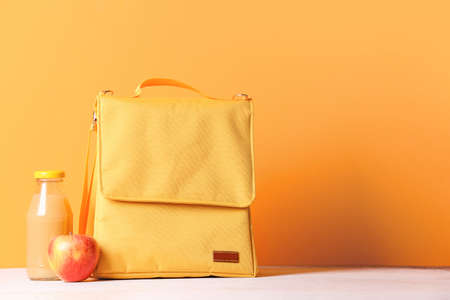 Lunch box bag, bottle of juice and apple on color backgroundの写真素材