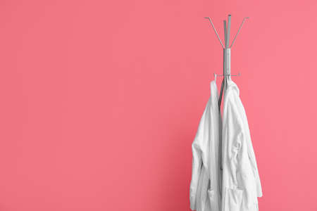 Rack with white bathrobes near pink wallの写真素材