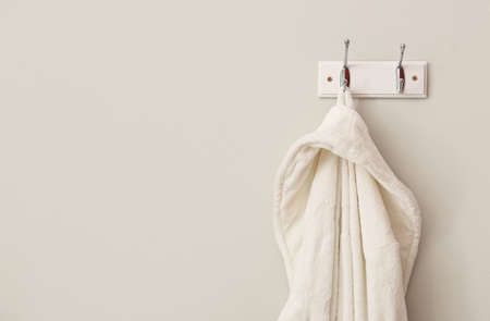 White bathrobe hanging on light wall, closeupの写真素材