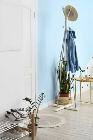 Rack with denim jacket and hat in interior of stylish hallwayの写真素材