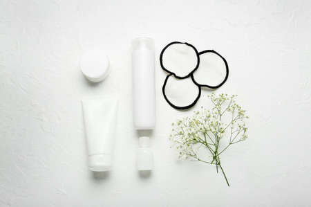 Reusable cotton pads, bottles of cosmetic products and flowers on light backgroundの写真素材