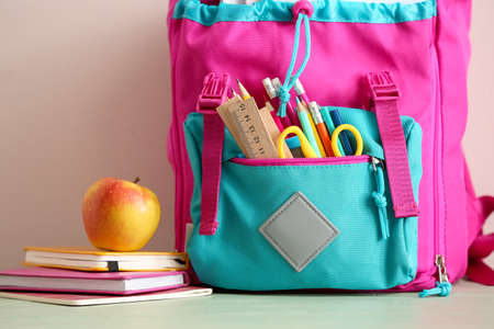 School backpack with stationery and apple on table, closeupの写真素材