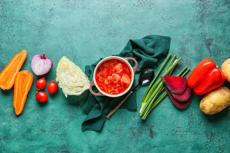 Pot of tasty borscht and ingredients on color backgroundの写真素材