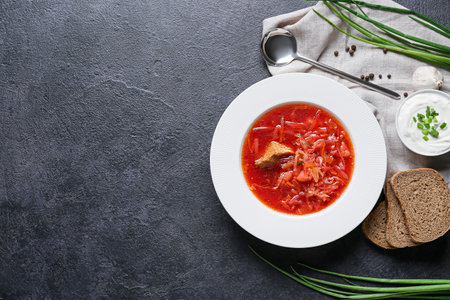 Plate of tasty borscht, sour cream and bread on dark backgroundの写真素材