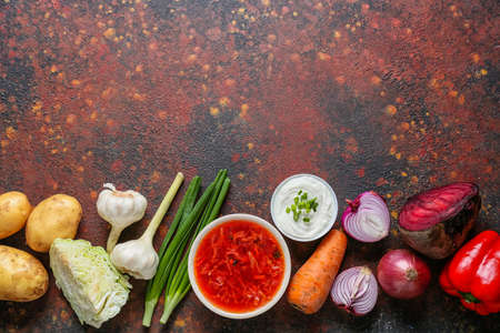 Bowl of tasty borscht and ingredients on grunge background