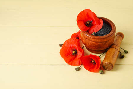 Mortar and pestle with poppy seeds and flowers on color wooden backgroundの写真素材