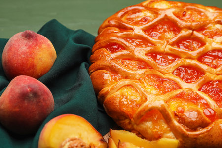 Tasty bun with peaches on napkin, closeup