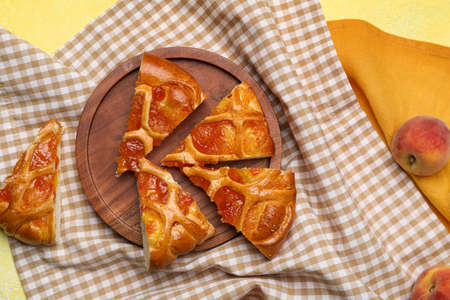 Board with slices of tasty peach bun on napkinの写真素材