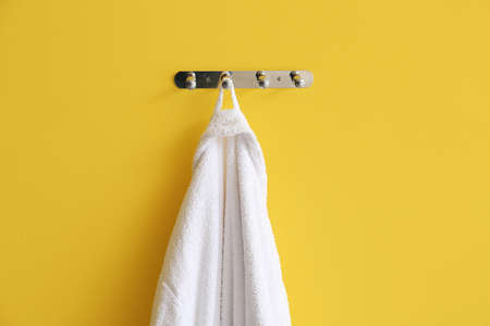 White bathrobe hanging on yellow wallの写真素材