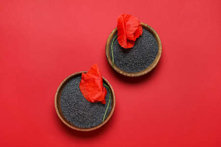 Bowls with poppy seeds and flowers on color backgroundの写真素材