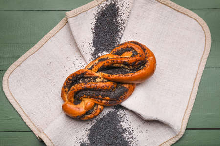 Napkin with tasty poppy seed bun on green wooden backgroundの写真素材