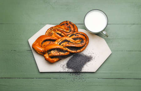Tasty poppy seed buns with glass of milk on green wooden backgroundの写真素材
