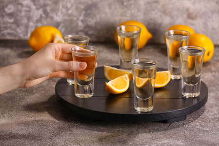 Woman with shot of tasty tequila and lemon on grunge background