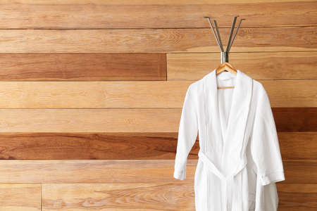 Rack with white bathrobes near wooden wallの写真素材