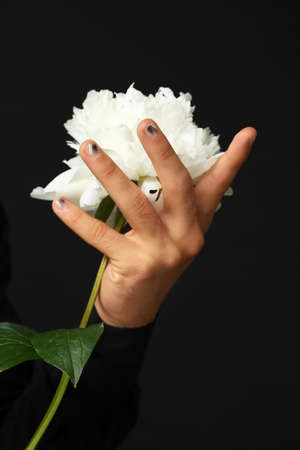 Male hand with stylish manicure and blooming flower on black background, closeupの写真素材