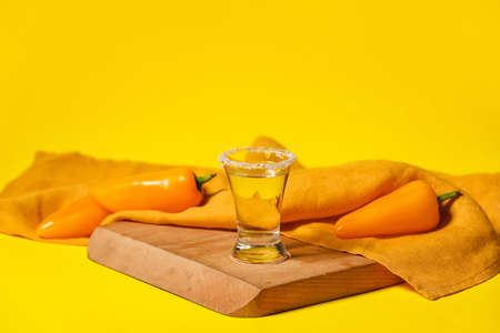 Board with shot of tasty tequila and chili pepper on color backgroundの写真素材