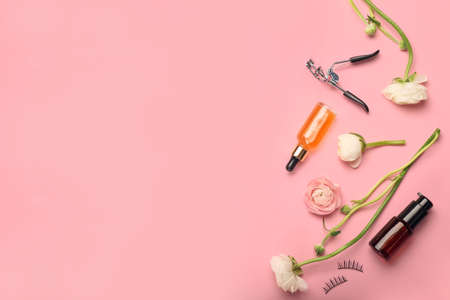 Composition with cosmetic products, eyelash curler and ranunculus flowers on pink background