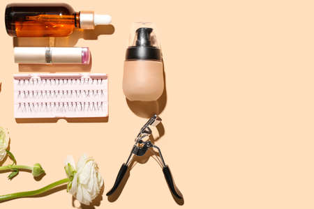 Composition with cosmetics, makeup supplies and ranunculus flowers on color background