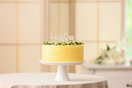 Stand with delicious wedding cake and word WEDDING on tableの写真素材