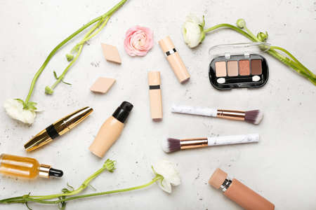 Set of decorative cosmetics, makeup sponges, brushes and ranunculus flowers on light backgroundの写真素材