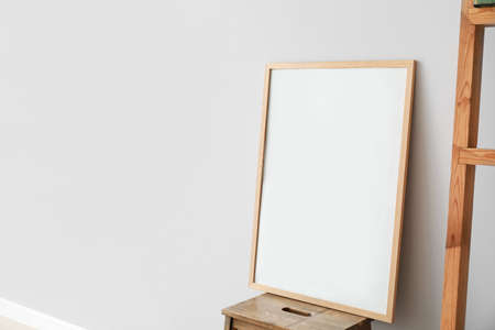 Blank poster on table near light wall