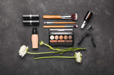 Composition with cosmetics, makeup supplies and ranunculus flowers on dark backgroundの写真素材