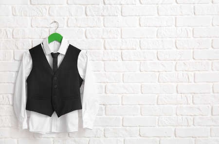Hanger with stylish school uniform on white brick wall in roomの写真素材