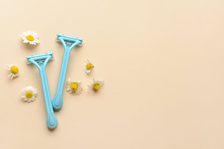 Safety razors and chamomile flowers on color background