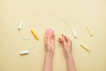 Female hands with menstrual cup and tampons on yellow backgroundの写真素材