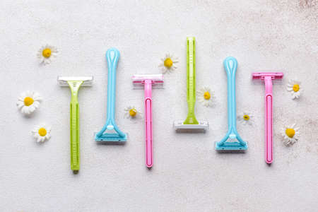 Different safety razors and chamomile flowers on light backgroundの写真素材