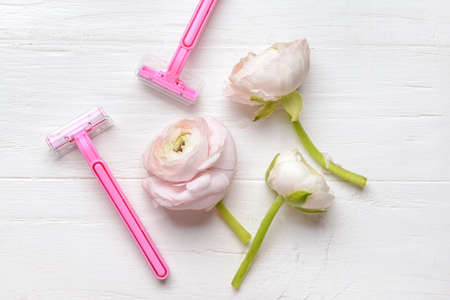 Safety razors and flowers on light wooden backgroundの写真素材