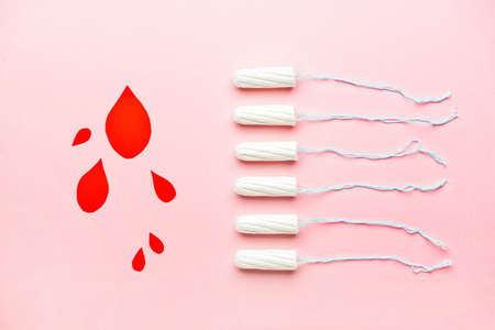 Menstrual tampons and paper blood drops on pink backgroundの写真素材