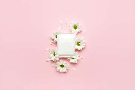 Menstrual pad and flowers on pink background