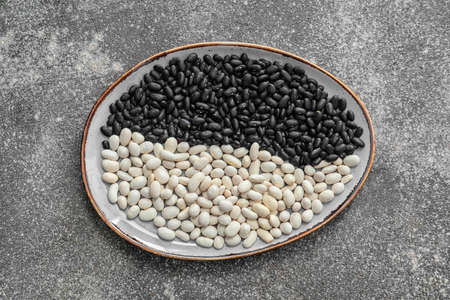 Plate with raw beans on grunge background