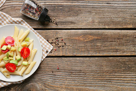 Plate of tasty pasta with vegetables on wooden background, closeupの写真素材