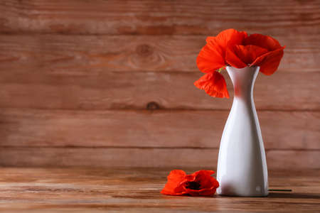 Vase with beautiful red poppy flowers on wooden backgroundの写真素材