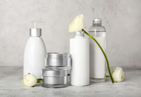 Bottles with cosmetics and ranunculus flowers on light backgroundの写真素材