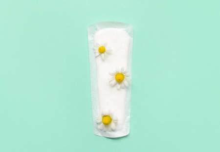 Menstrual pad and chamomile flower on green backgroundの写真素材