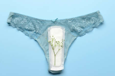 Menstrual pad, panties and flowers on blue backgroundの写真素材