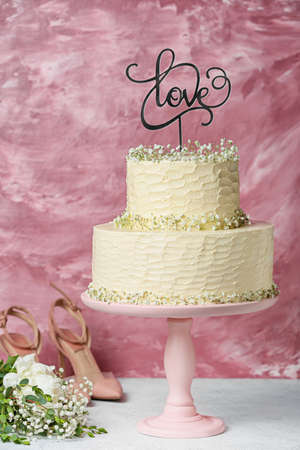 Dessert stand with beautiful wedding cake and topper with word LOVE on tableの写真素材