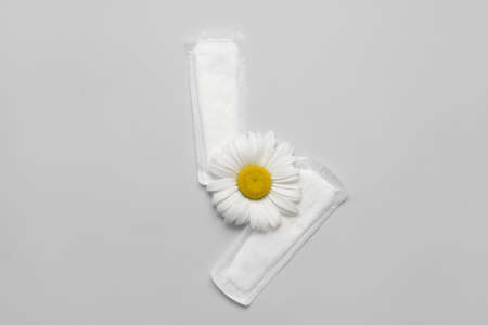Menstrual pad and chamomile flower on light backgroundの写真素材