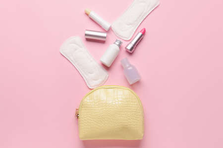 Bag with menstrual pads and cosmetics on pink backgroundの写真素材