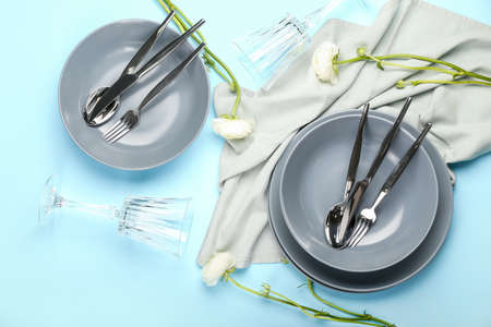 Simple table setting and ranunculus flower on color background